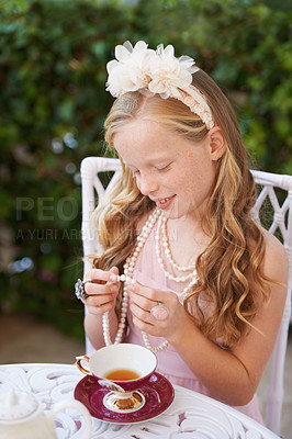 Buy stock photo A girl playing dress up in her garden with a ea cup in front of her