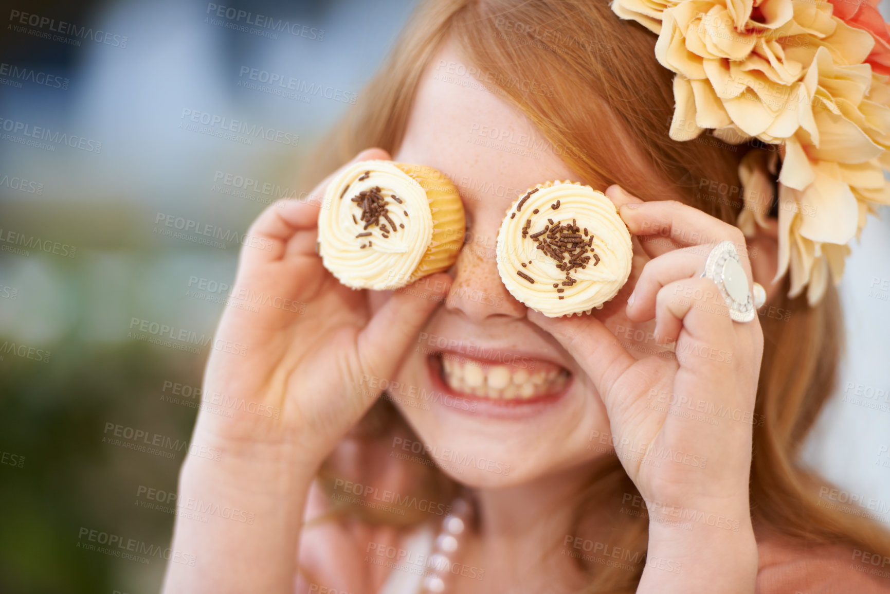 Buy stock photo A little girl playfully holding cupcakes in front of her eyes