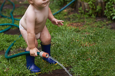 Buy stock photo Baby, playing with hose and water, backyard and  development with growth, curiosity and home. Toddler, child and infant in garden, alone and childhood for wellness, milestone and coordination