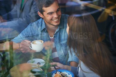Buy stock photo Shot of a young couple drinking coffee and talking in a cafe
