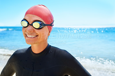 Buy stock photo A young woman training in a full piece wetsuit and swimming gear on the beach in the winter