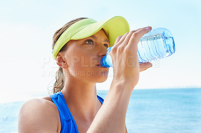 Buy stock photo An attractive and athletic young woman drinking water after a run