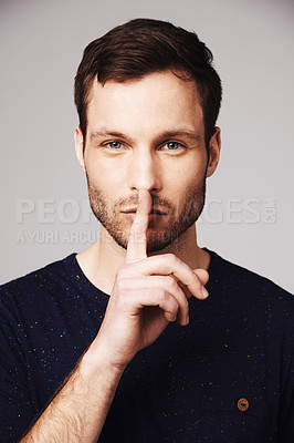 Buy stock photo Man, secret and portrait with silence, hand and finger emoji sign in a studio. Isolated, gossip and whisper of a young male model face with confidential, lips and person with privacy and stop gesture