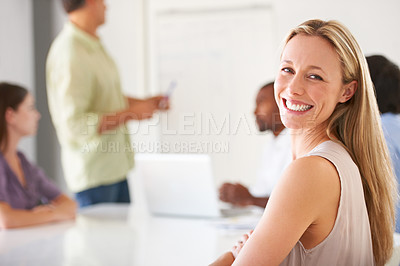 Buy stock photo A smiling businesswoman looking at you while in a team meeting