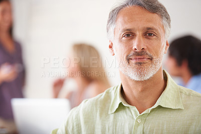 Buy stock photo Handsome mature businessman looking composed with his coworkers blurred in the background