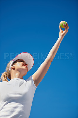 Buy stock photo A young tennis player serving during a match