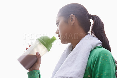 Buy stock photo A young ethnic woman drinking a sports drink outdoors