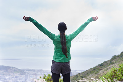Buy stock photo Rearview of an adventurous young woman standing with her arms outstretched on the mountain