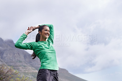 Buy stock photo A young ethnic woman stretching while looking at the views from the mountain peak