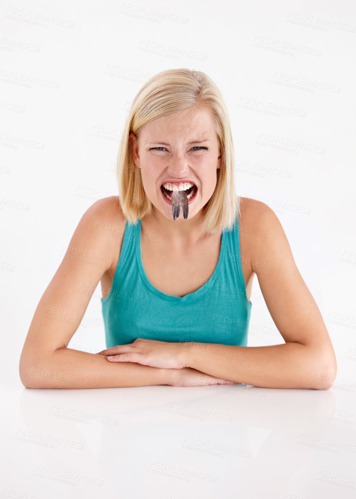 Buy stock photo Crazy, woman and portrait of eating fish, tail or strange food in mouth on white background of studio. Dislike, diet and person with weird seafood, cuisine and disgust for taste of tuna or salmon