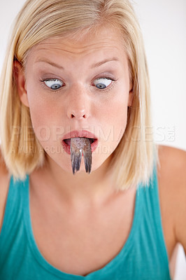 Buy stock photo Shocked, woman and eating of fish with surprise on face in white background of studio. Crazy, diet and hungry person with horror at weird seafood, cuisine and disgust in mouth for gross food