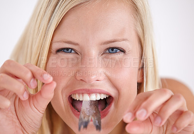 Buy stock photo Funny, woman and portrait of eating fish, tail or strange food in mouth on white background of studio. Crazy, diet and person taste weird seafood, cuisine and taste a bite of tuna or salmon meat