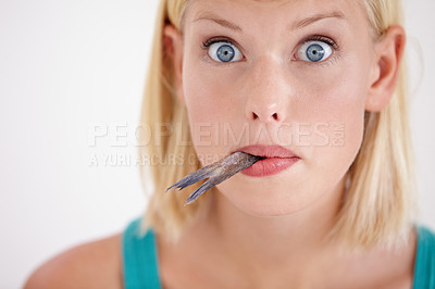 Buy stock photo Portrait of a young woman eating a whole fish
