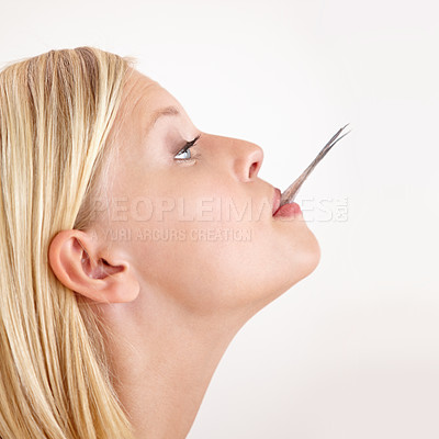 Buy stock photo Woman, eating and tail of fish in mouth or hungry for strange food in white background, studio or mockup. Crazy, diet and person bite weird seafood, cuisine and try a taste of tuna or salmon meat 