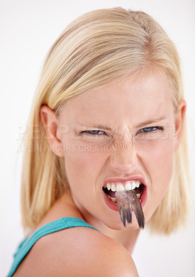 Buy stock photo Woman, eating and portrait with fish, tail or dislike strange food in mouth on white background of studio. Crazy, diet and person with weird seafood, cuisine and disgust for taste of tuna or salmon