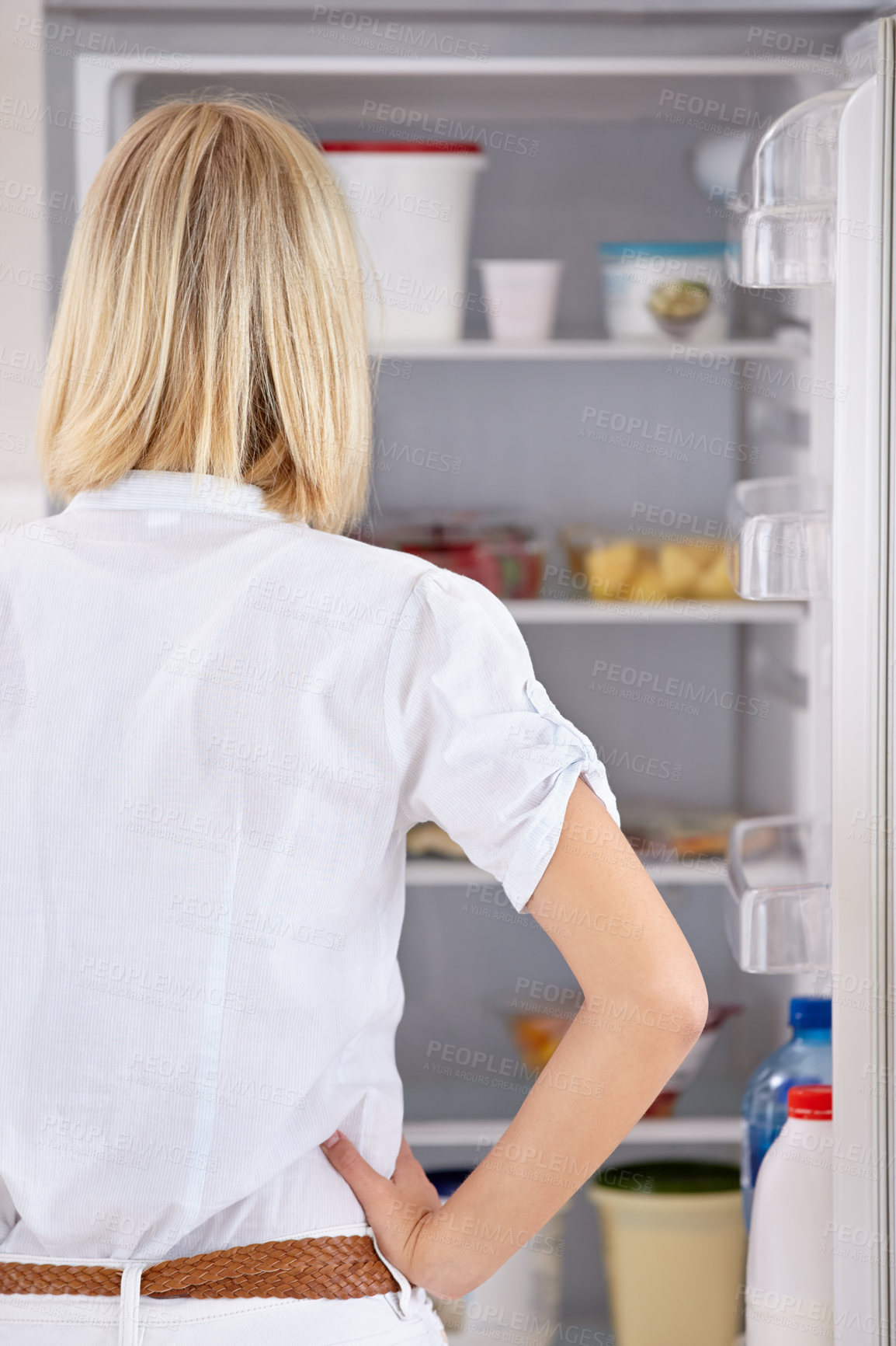 Buy stock photo Rearview of a young woman looking in her fridge