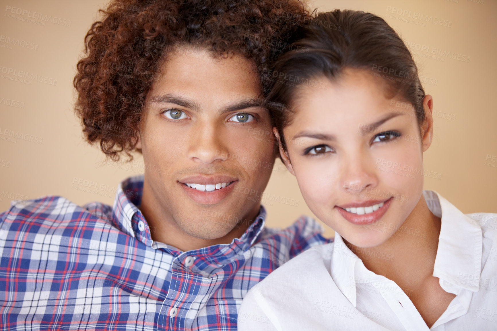 Buy stock photo Studio portrait of a happy young ethnic couple sitting side by side smiling at the camera