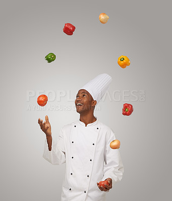 Buy stock photo A young African-American chef juggling with vegetables