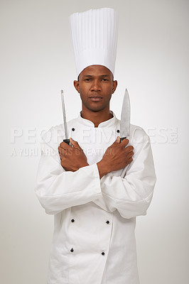 Buy stock photo Portrait, african chef and knives in studio in hospitality career and confident cook in food industry. Black man, face and serious in skill in kitchen utensils and uniform by hat by white background