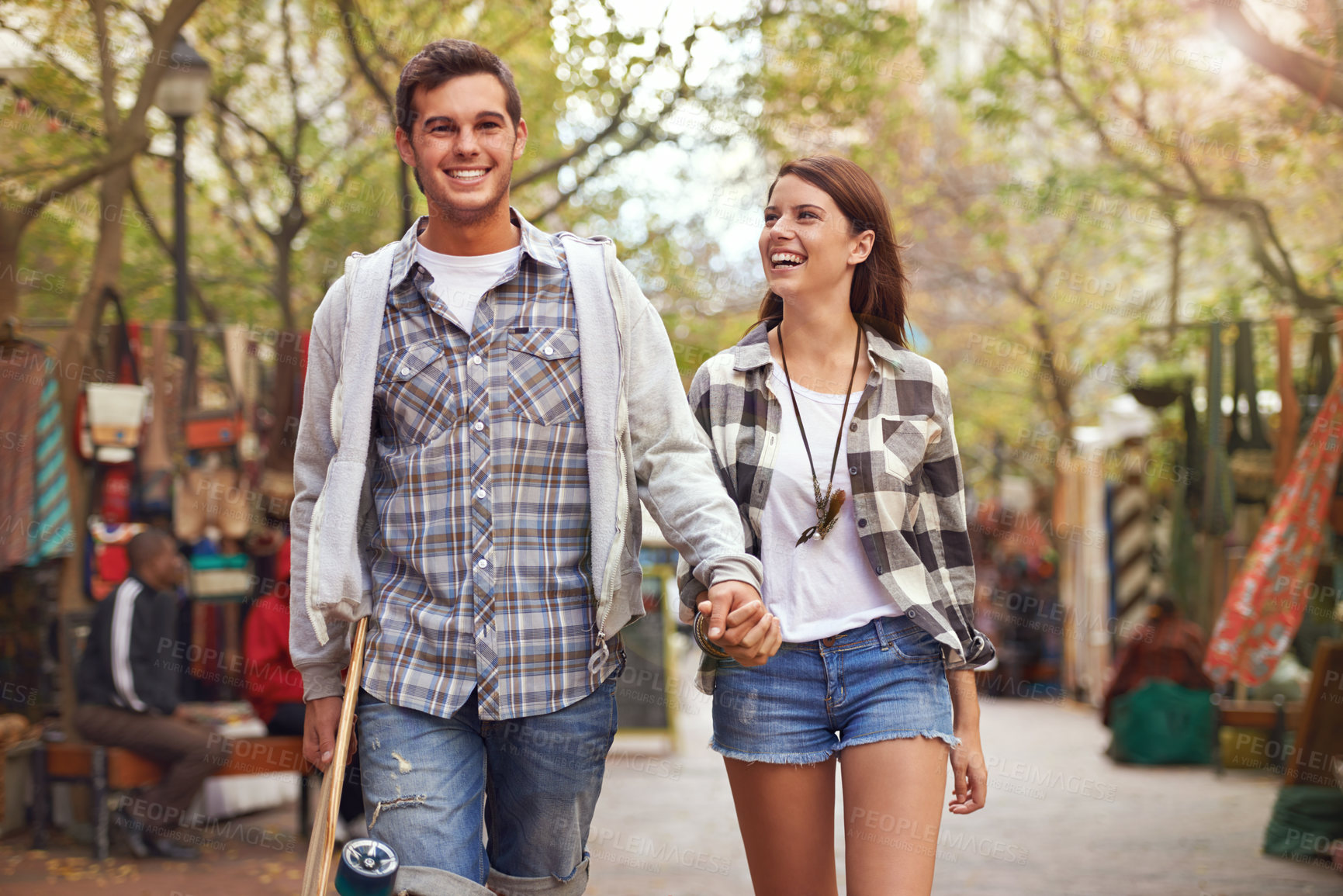 Buy stock photo Smile, walking and couple holding hands on city journey, morning trip or weekend tour of urban Spain for outdoor adventure. Love, skateboard and young people bonding together on relax commute