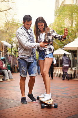 Buy stock photo Skateboard ride, happy and couple teaching girlfriend how to balance, exercise lesson or training in urban Spain. Skate, fun and skateboarder helping, coaching and smile for skateboarding development