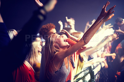 Buy stock photo A group of people standing with their arms raised at a concert