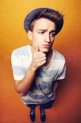 Buy stock photo Thinking, face and man with fashion, hat and gesture in studio with confidence on orange background. Questions, emoji and male model with attitude, personality or trend, cool and fashionable outfit