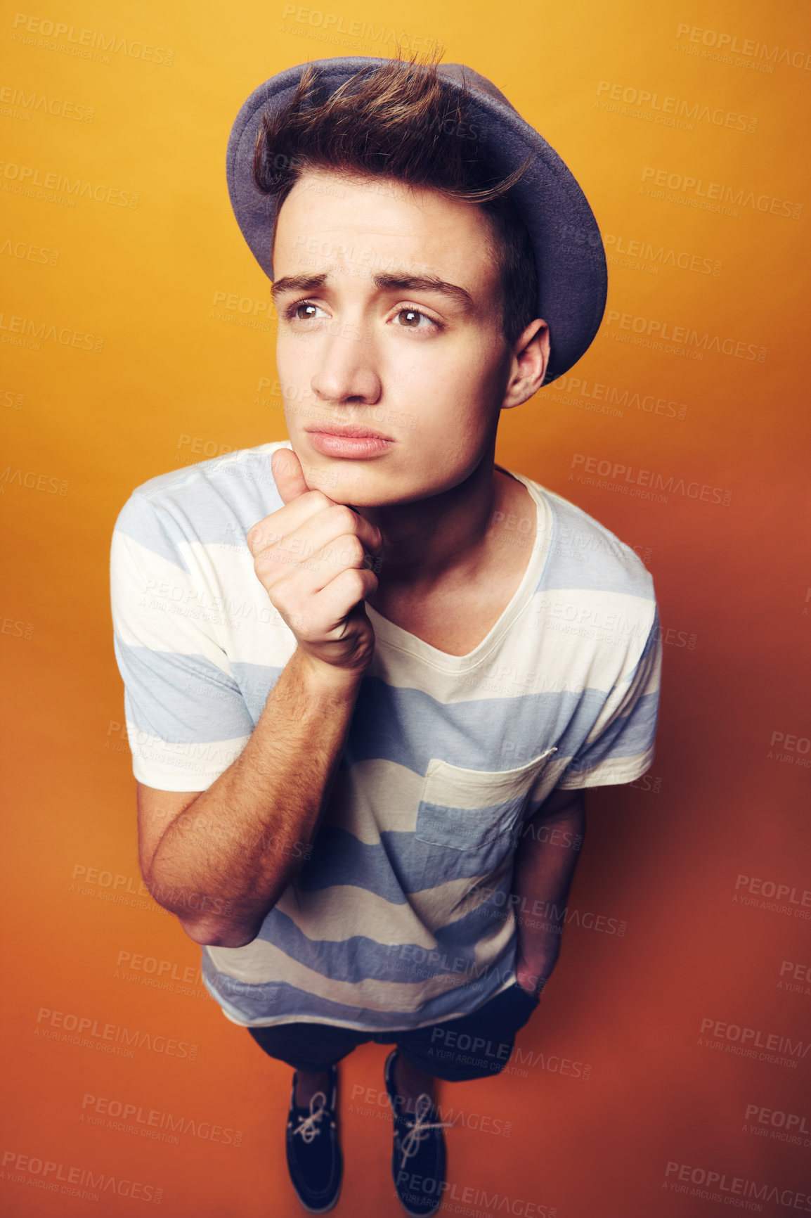 Buy stock photo Face, thinking and man with fashion hat and gesture in studio with confidence on orange background. Questions, emoji and male model with attitude, personality or trend, cool and fashionable outfit