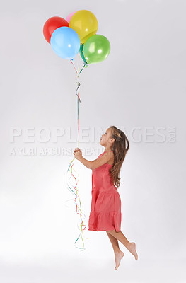 Buy stock photo A young girl being lifted in the air by a bunch of colourful balloons