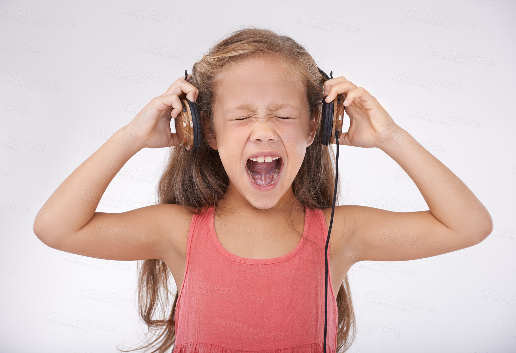 Buy stock photo Child, headphones and screaming in studio for music entertainment, rock or streaming. Female person, girl and shout for listening audio or radio noise or loud sing, white background or mockup space