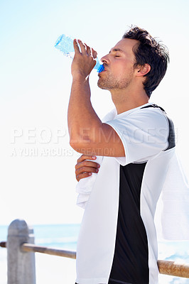 Buy stock photo Man, fitness and drinking water for hydration, health or wellness after workout, exercise or training at the beach. Fit, active and thirsty male having a drink in break or refreshment from exercising