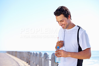 Buy stock photo A young man taking a water break while exercising outside