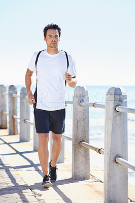 Buy stock photo Man, fitness and running by the beach for exercise, workout or training in the nature outdoors. Fit, active or athletic male runner exercising on the ocean coast for run, healthy cardio and wellness