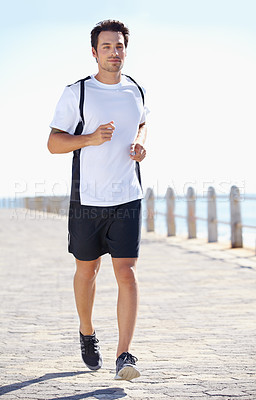 Buy stock photo Man, fitness and running by the beach for workout, exercise or training in the nature outdoors. Fit, active or athletic male runner exercising on the ocean coast for run, healthy cardio and wellness