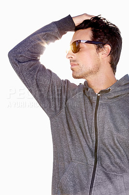Buy stock photo Low angle shot of a handsome young man wearing sunglasses and running his hand through his hair