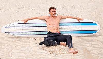 Buy stock photo Relax, vision and laughing man with surfboard on beach in wetsuit for sports, travel or fitness. Thinking, smile and body of young surfer on sand by ocean or sea for break from training and exercise