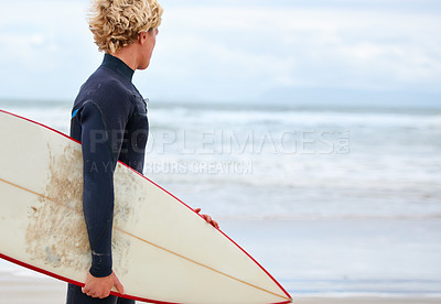 Buy stock photo A young surfer standing on the beach with the ocean in the background