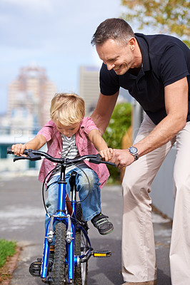Buy stock photo Bicycle, teaching and father with boy child in a road for help, learning or outdoor ride together. Love, family or parent with kid in a street for cycling assistance, bonding and support or safety