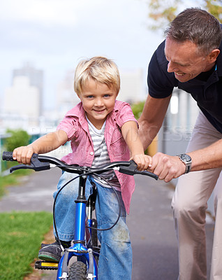Buy stock photo A father teaching his young son to ride a bike