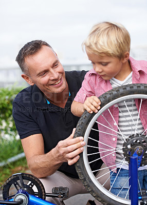 Buy stock photo Bicycle, wheel or repair with father and son outdoor in neighborhood for learning or child development. Family, street and fixing with man parent teaching young boy tyre maintenance for cycling