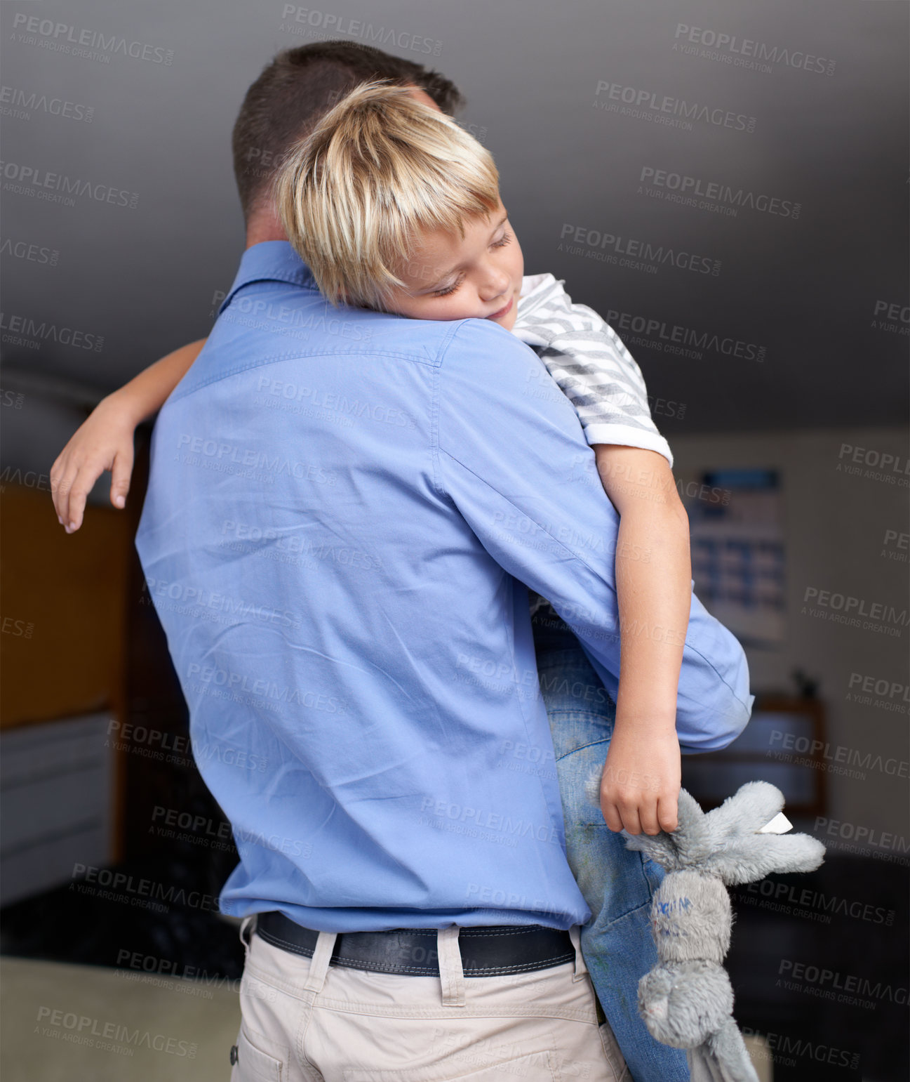 Buy stock photo A mature father coming home from work and hugging his exhausted little boy
