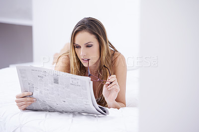 Buy stock photo Woman, relax and reading newspaper on bed for morning, wakeup or literature on break at home. Young attractive female person or journalist lying in bedroom with paper for news or information at house