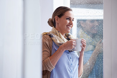 Buy stock photo An attractive young woman standing by the window and drinking coffee