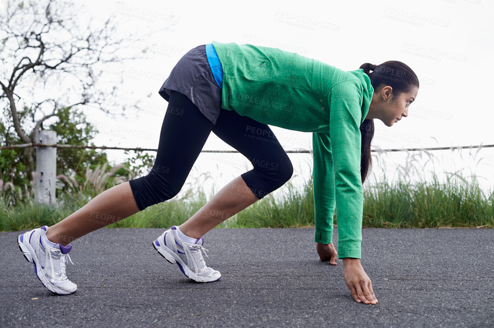 Buy stock photo A young woman crouching on the street about to go for a run