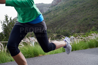 Buy stock photo Cropped shot of a woman sprinting along a mountain road on a crisp morning
