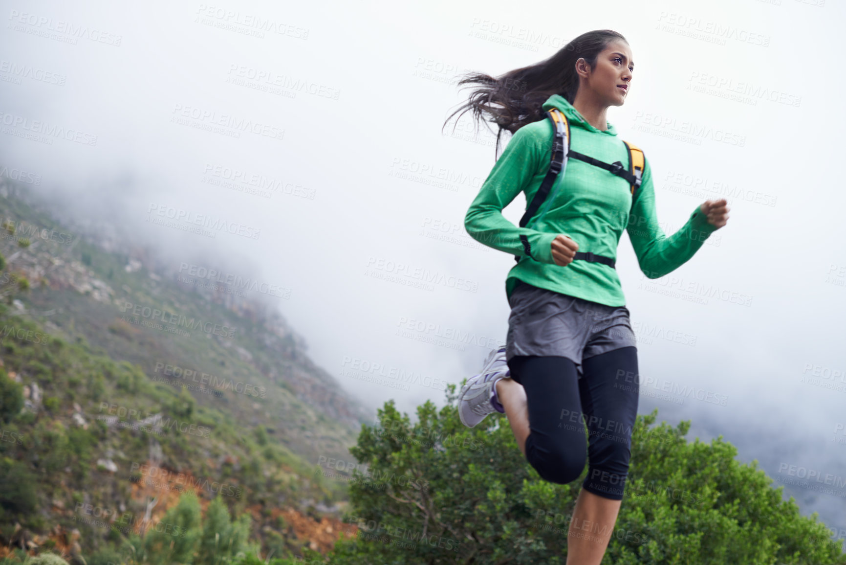 Buy stock photo A young woman sprinting along a mountain road on a crisp morning