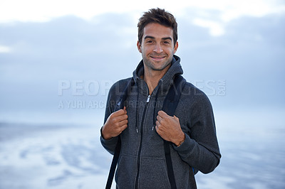 Buy stock photo A handsome young man standing on the beach at evening time