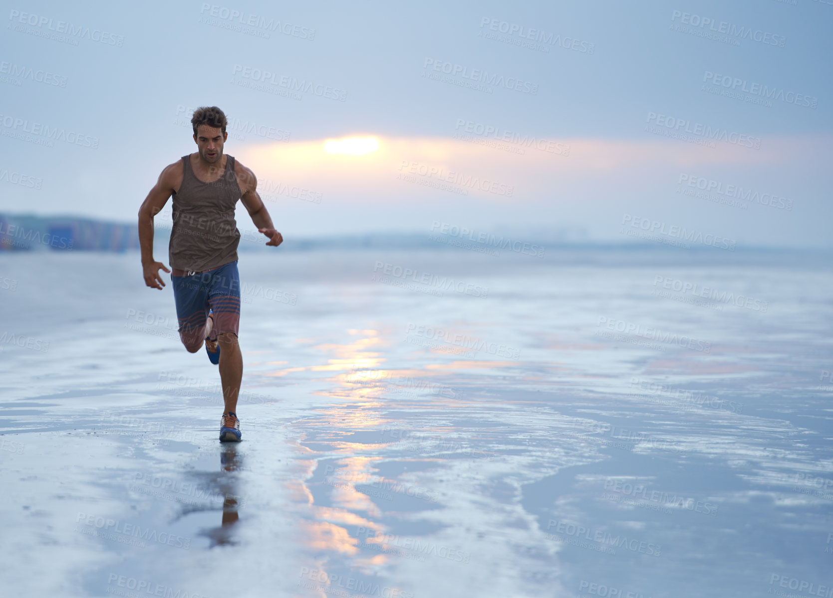 Buy stock photo A handsome young man exercising on the beach in the early morning