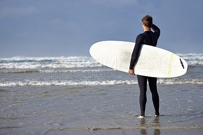 Buy stock photo Shot of a young man about to go surfing 