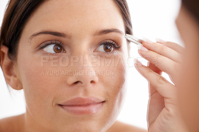 Buy stock photo An attractive young woman plucking her eyebrows
